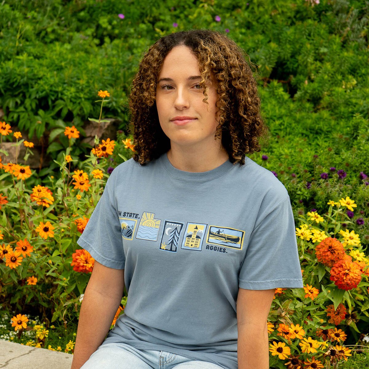 Young woman wearing blue Utah State stamp t-shirt outside